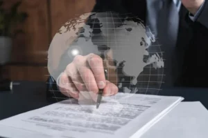 دست شخصی در حال امضا یک سند و نمادی از کره زمین به نشانه فعالیت تجاری و بین المللی